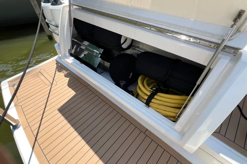 Esquire Yacht Photos Pics 2017 Riviera 3600 Sport Yacht storage compartment with coiled yellow hose and equipment.