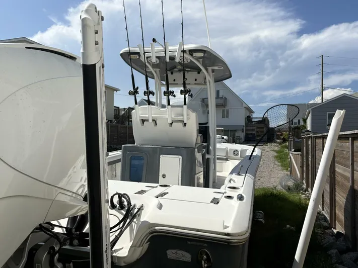  Yacht Photos Pics 2019 Tidewater 2700 Carolina Bay boat with fishing rods, parked near houses under a blue sky.