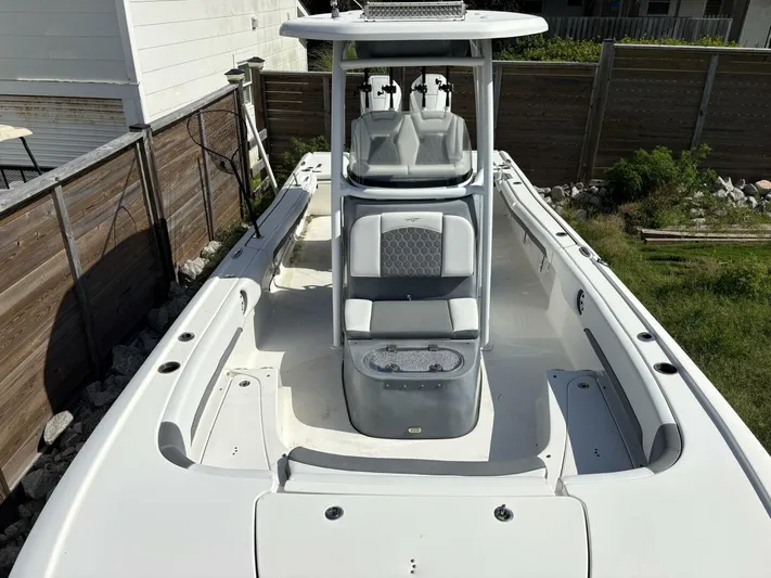  Yacht Photos Pics 2019 Tidewater 2700 Carolina Bay boat with center console and seating, docked near a wooden fence.