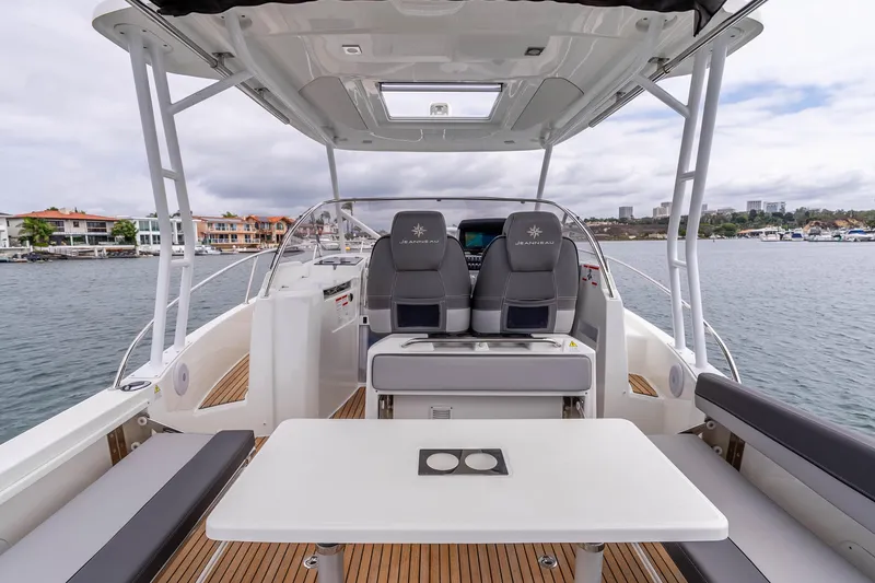  Yacht Photos Pics 2023 Jeanneau Leader 9.0 WA boat interior with seating and table, docked by waterfront homes.