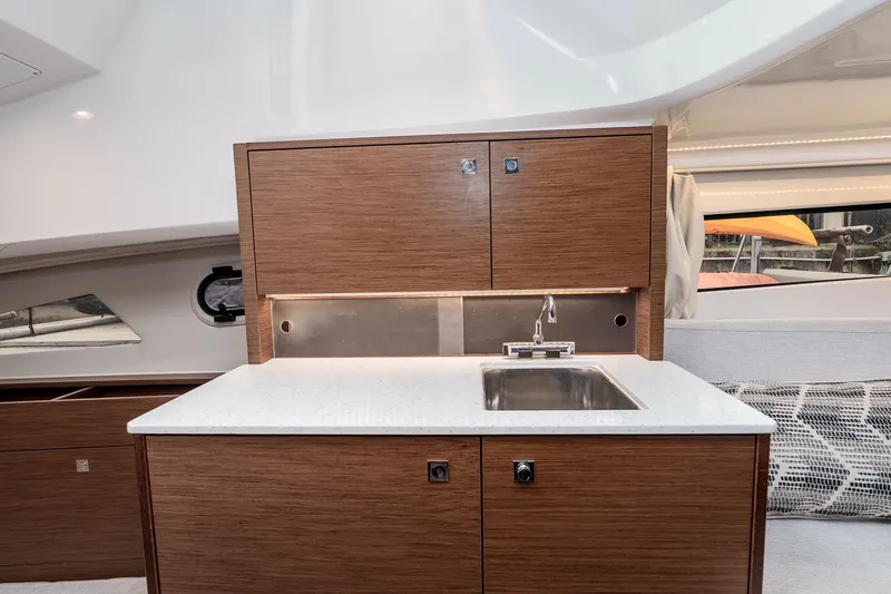  Yacht Photos Pics Modern kitchenette in 2023 Jeanneau Leader 9.0 WA boat with wood cabinetry and stainless steel sink.