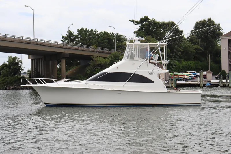  Yacht Photos Pics 2004 Ocean Yachts 43 Super Sport cruising on a calm river near a bridge.