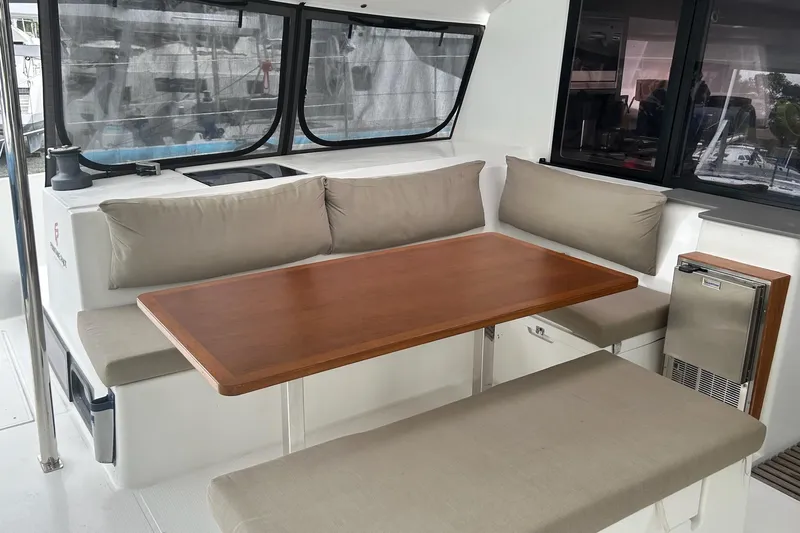  Yacht Photos Pics 2019 Fountaine Pajot Helia 44 Evolution yacht interior with cushioned seating and wooden table.