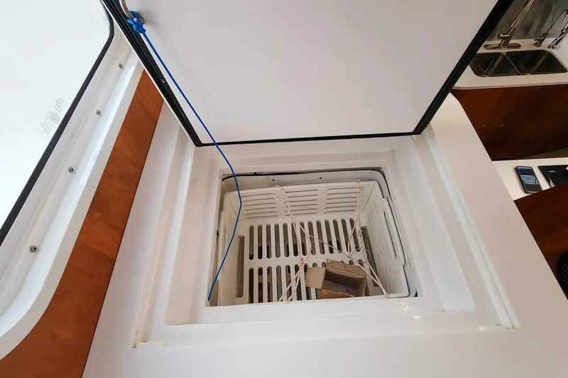 Cinnamon Yacht Photos Pics Open storage compartment on 2019 Antares 44GT boat, featuring a white interior and blue cord.
