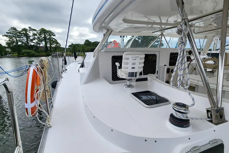 Cinnamon Yacht Photos Pics 2019 Antares 44GT yacht deck with seating, ropes, and life preserver by a calm river.