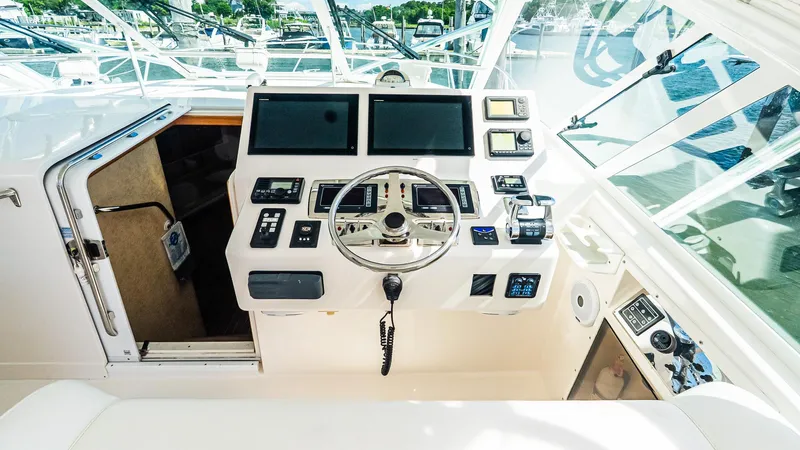  Yacht Photos Pics 2008 Cabo 38 Express helm with modern navigation equipment and steering wheel, docked at marina.