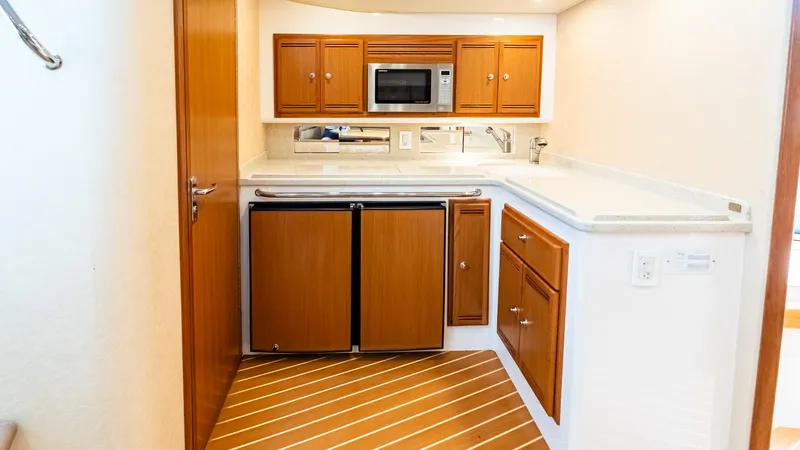  Yacht Photos Pics 2008 Cabo 38 Express yacht kitchen with wooden cabinets, microwave, and compact fridge.