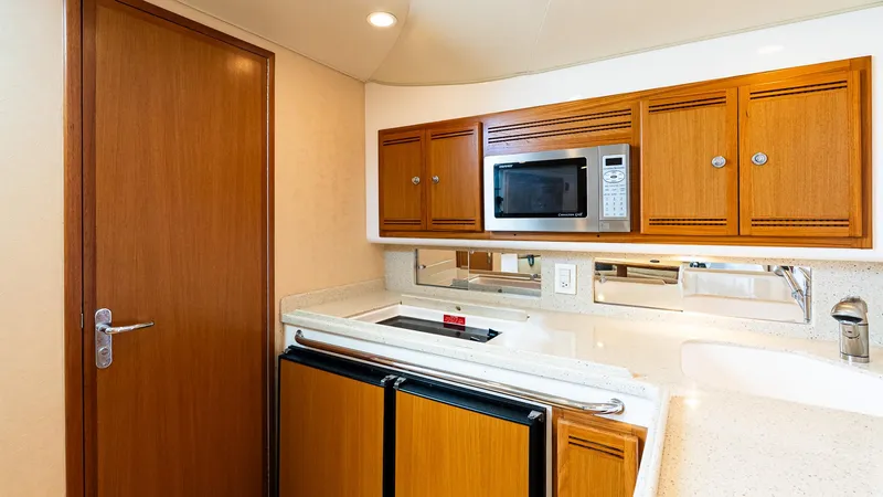  Yacht Photos Pics 2008 Cabo 38 Express yacht kitchen with wood cabinets, microwave, and compact fridge.