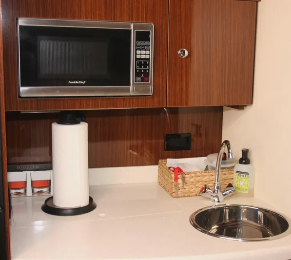 Sapphire Yacht Photos Pics 2014 Regal 38 Express yacht kitchenette with microwave, sink, and wooden cabinetry.