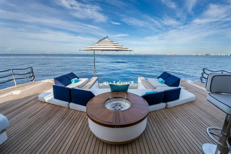 King's Lair Yacht Photos Pics Luxurious 2023 Benetti 34M OASIS yacht deck with seating, ocean view, and umbrella.