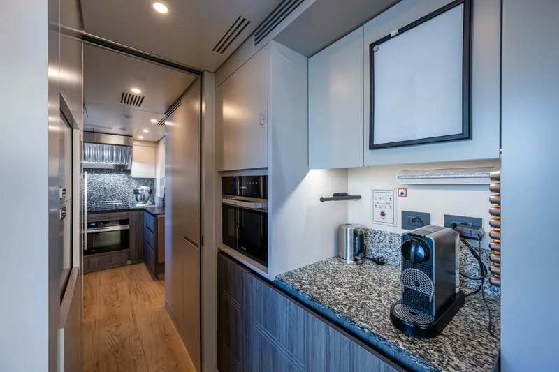 King's Lair Yacht Photos Pics Modern kitchen interior on 2023 Benetti 34M OASIS yacht, featuring sleek appliances and granite countertops.