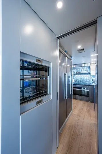 King's Lair Yacht Photos Pics Modern kitchen interior of 2023 Benetti 34M OASIS yacht, featuring sleek appliances and wood flooring.