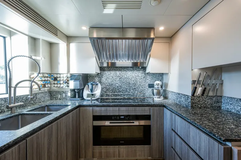 King's Lair Yacht Photos Pics Modern kitchen in 2023 Benetti 34M OASIS yacht with granite countertops and stainless steel appliances.