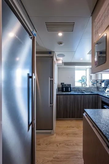 King's Lair Yacht Photos Pics Modern kitchen interior on 2023 Benetti 34M OASIS yacht, featuring sleek appliances and wood flooring.