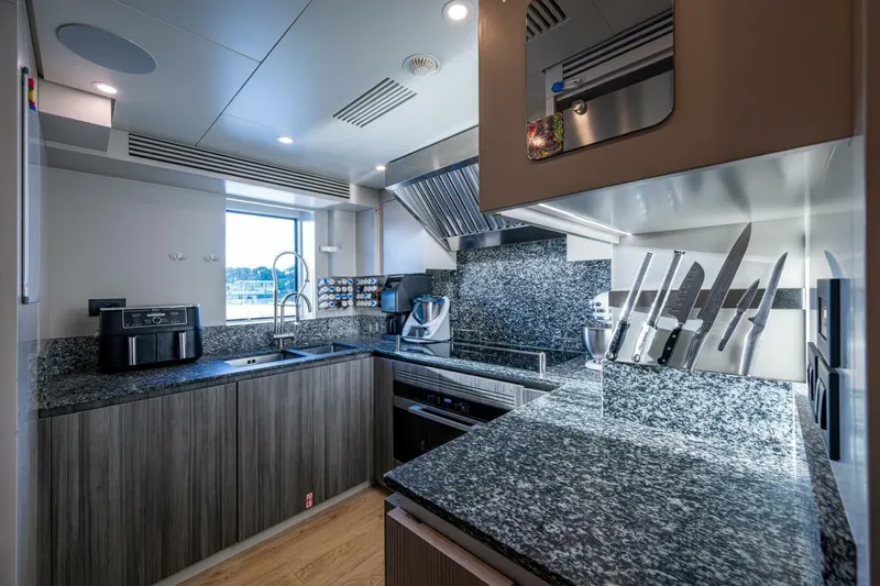 King's Lair Yacht Photos Pics Modern kitchen in 2023 Benetti 34M OASIS yacht with granite countertops and stainless steel appliances.