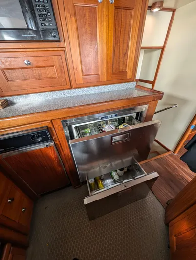 Good Job Yacht Photos Pics 2002 Nordhavn Trawler kitchen with open stainless steel drawer fridge, wooden cabinets, and microwave.