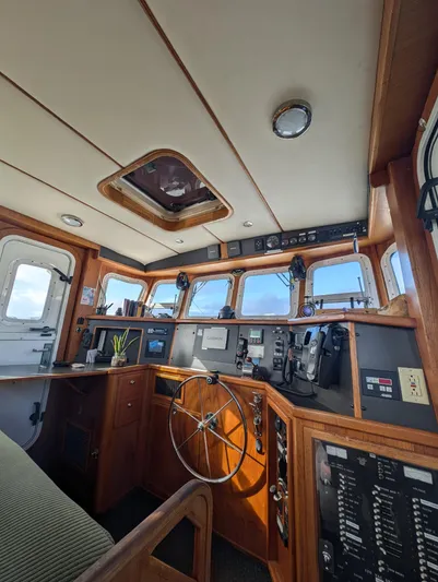 Good Job Yacht Photos Pics 2002 Nordhavn Trawler helm with navigation equipment, wooden interior, and panoramic windows.
