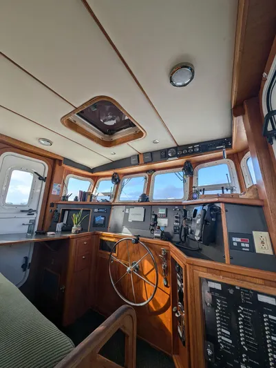 Good Job Yacht Photos Pics 2002 Nordhavn Trawler helm with wooden interior, navigation equipment, and panoramic windows.