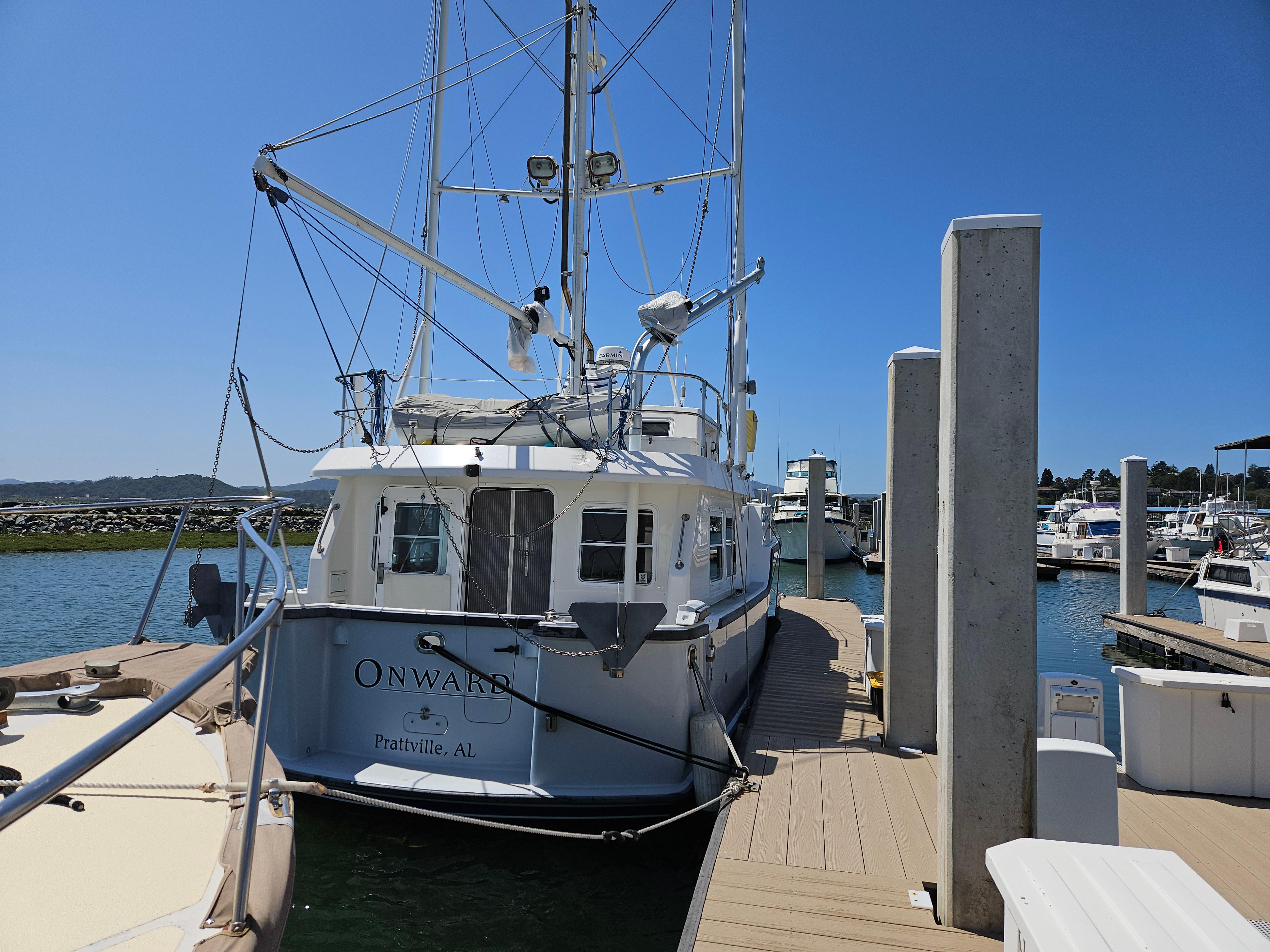 2002 Nordhavn Trawler docked at marina under clear blue sky.