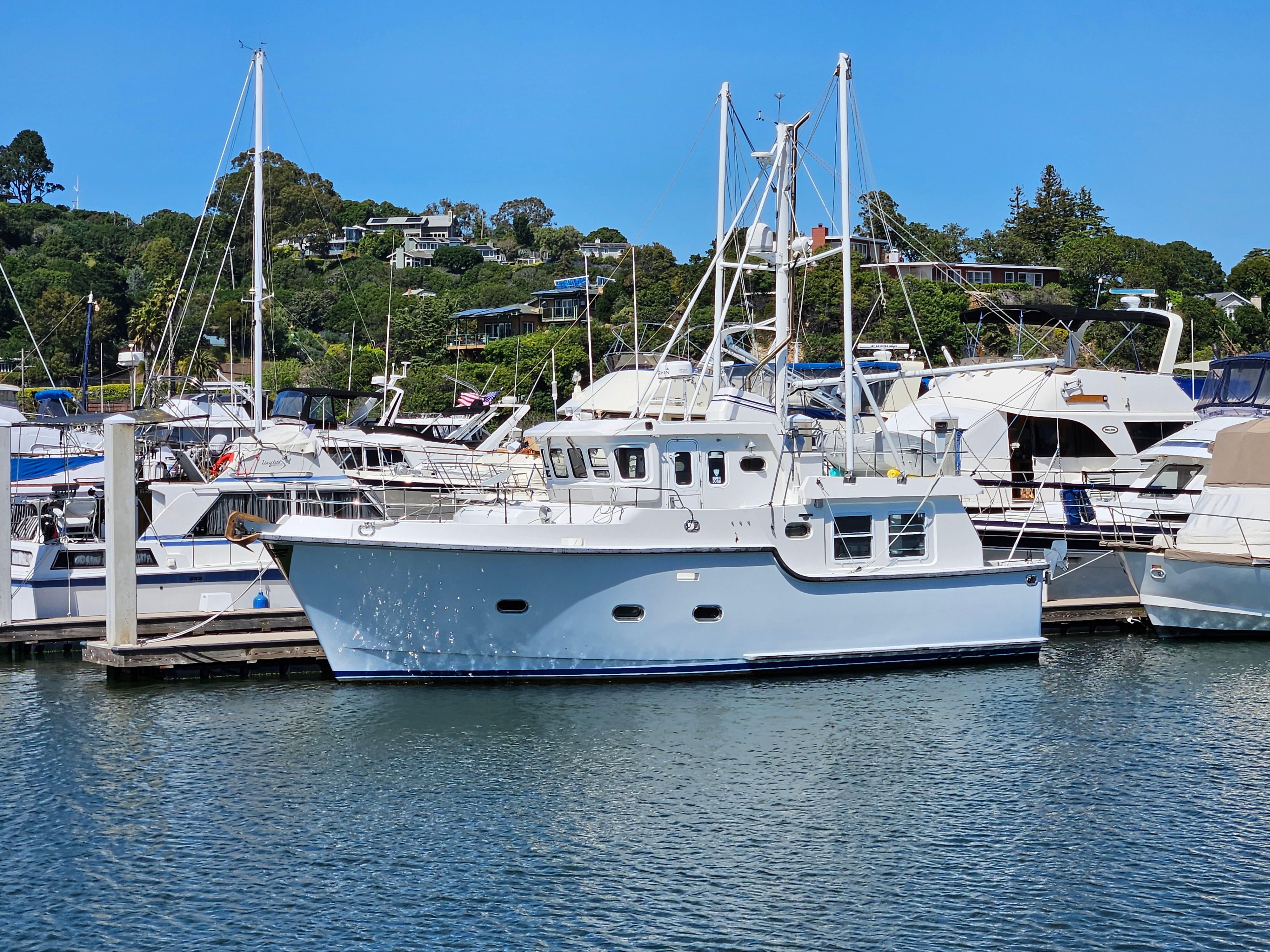 2002 Nordhavn Trawler docked in a marina, surrounded by other boats, under a clear blue sky.