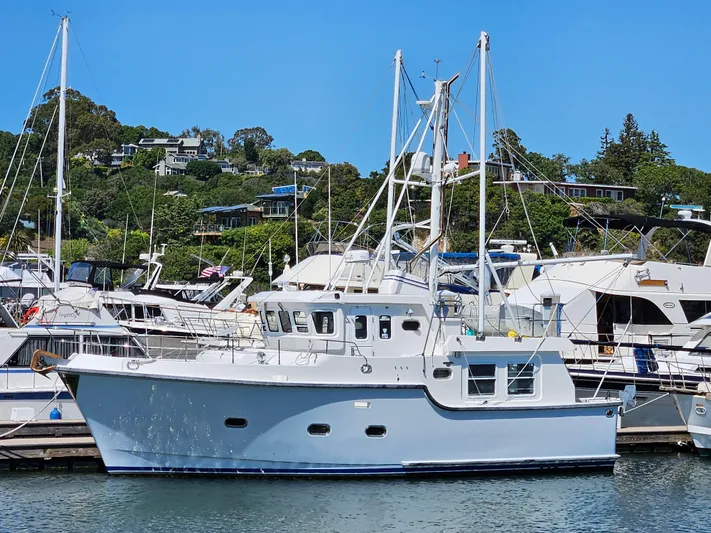 Good Job Yacht Photos Pics 2002 Nordhavn Trawler docked at marina, surrounded by other boats, with hillside homes in background.