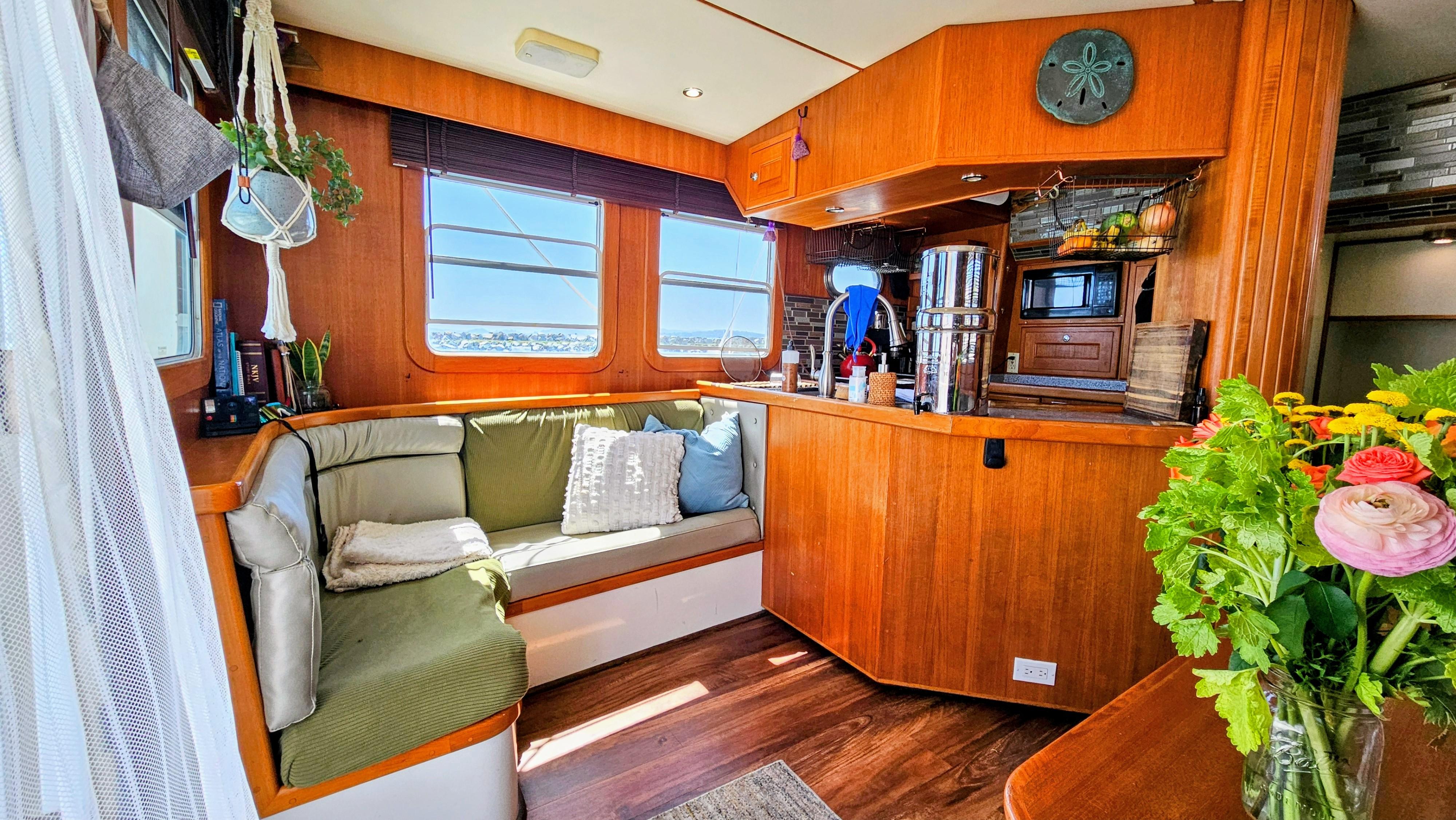 Cozy 2002 Nordhavn Trawler interior with wooden decor, seating area, and vibrant flowers.