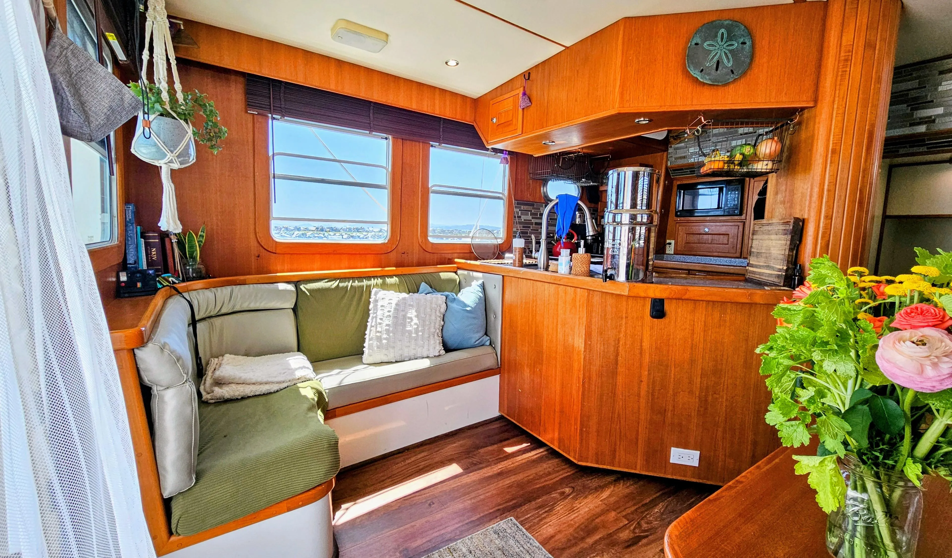 Cozy 2002 Nordhavn Trawler interior with wooden decor, seating area, and vibrant flowers.