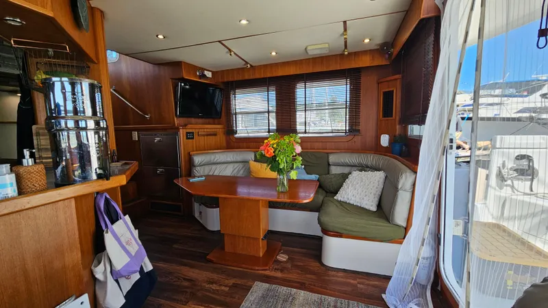 Good Job Yacht Photos Pics Luxurious 2002 Nordhavn Trawler interior with cozy seating, wooden accents, and a vibrant floral centerpiece.