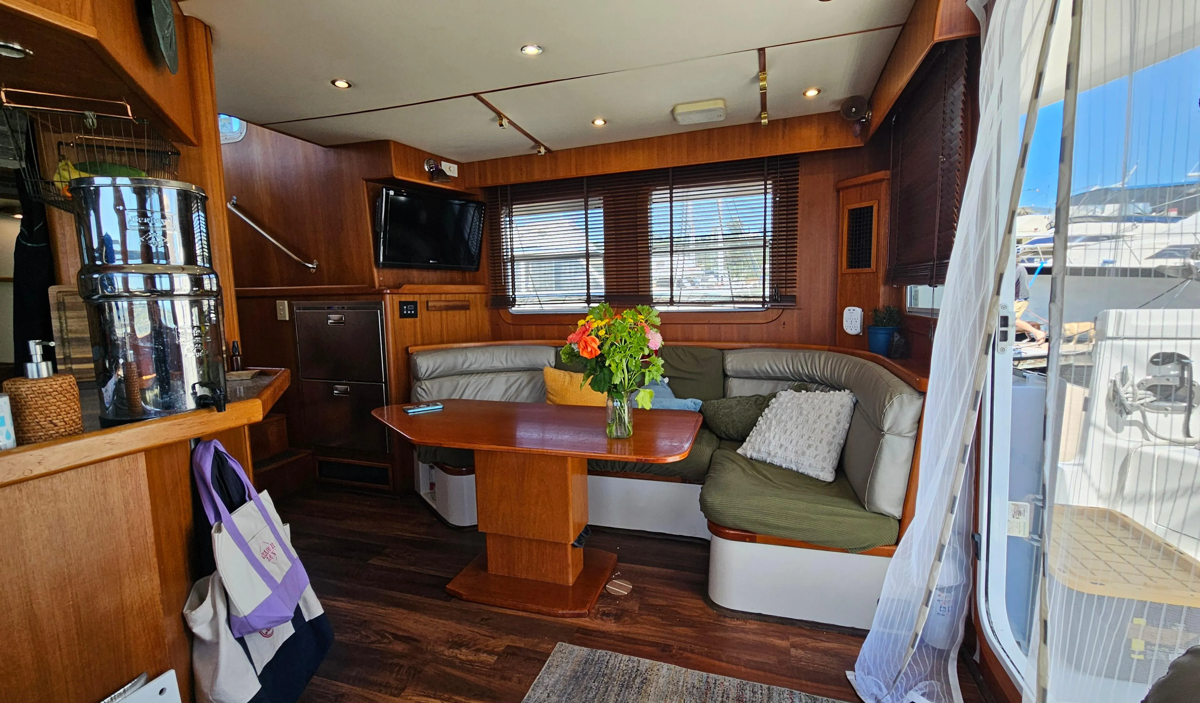 Luxurious 2002 Nordhavn Trawler interior with cozy seating, wooden accents, and a vibrant floral centerpiece.