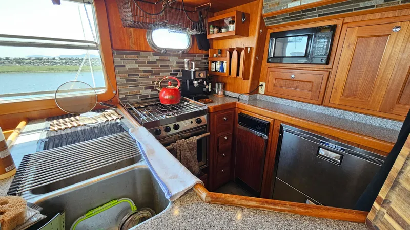 Good Job Yacht Photos Pics 2002 Nordhavn Trawler kitchen with stove, sink, and wooden cabinetry.