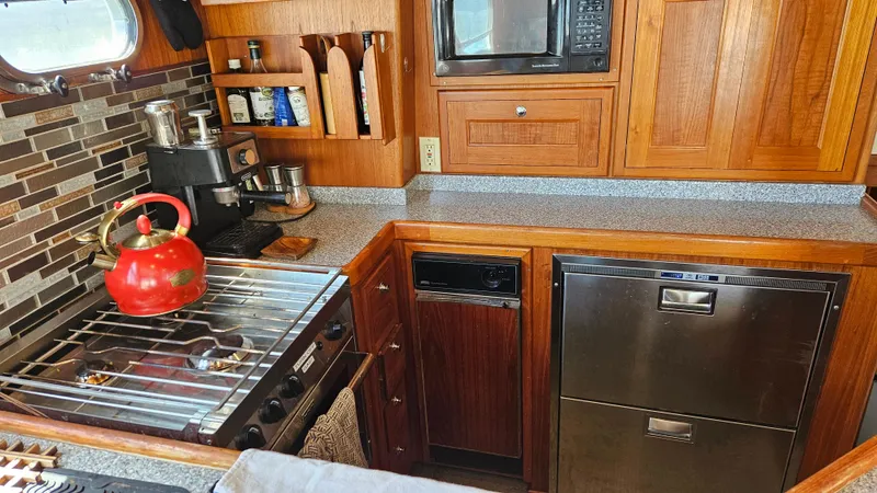 Good Job Yacht Photos Pics 2002 Nordhavn Trawler kitchen with stove, red kettle, microwave, and wooden cabinetry.