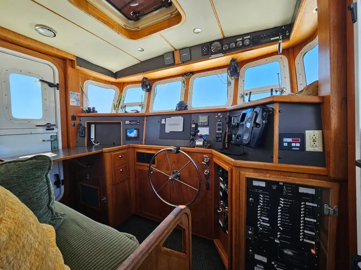Good Job Yacht Photos Pics 2002 Nordhavn Trawler helm with wooden interior, navigation instruments, and panoramic windows.