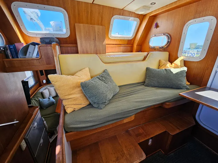 Good Job Yacht Photos Pics Cozy interior of a 2002 Nordhavn Trawler with cushioned seating and wooden accents.