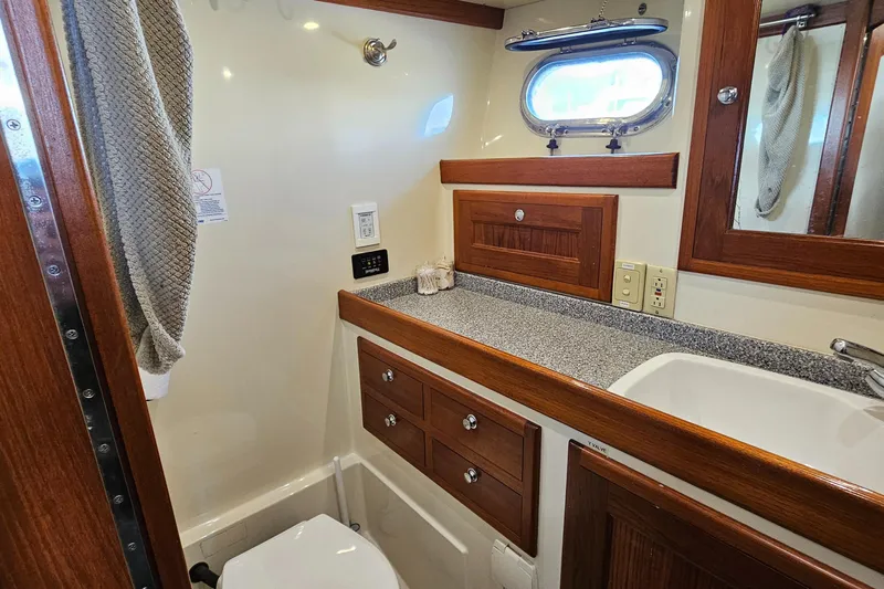 Good Job Yacht Photos Pics 2002 Nordhavn Trawler bathroom with wood accents, sink, and porthole window.