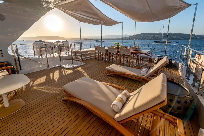 Lady H Yacht Photos Pics Luxurious Benetti Majesty 120 yacht deck with sun loungers and dining area at sunset, 2011 model.