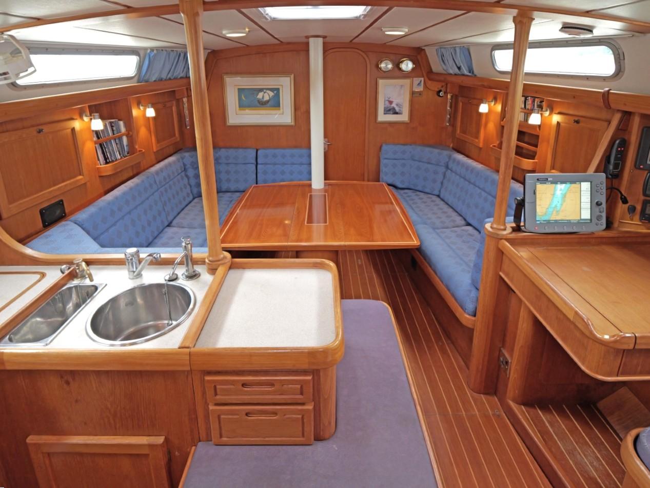Luxurious 1999 Rustler 42 yacht interior with wood finish and blue seating.