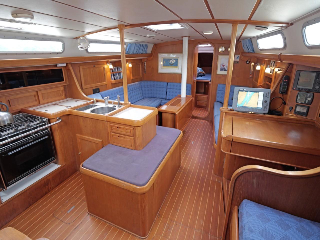 Interior of a 1999 Rustler 42 yacht with wooden furnishings and blue seating.