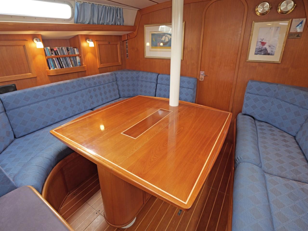 Interior of 1999 Rustler 42 yacht with wooden table and blue seating.