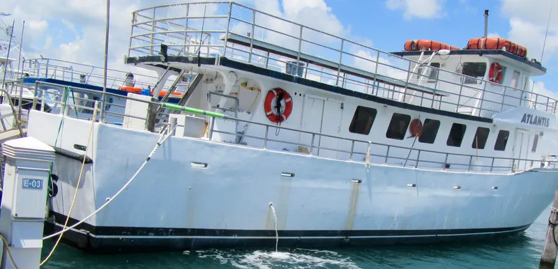 Atlantis Yacht Photos Pics White commercial fishing boat docked, 1986 Drift Fishing Party model, under a blue sky.