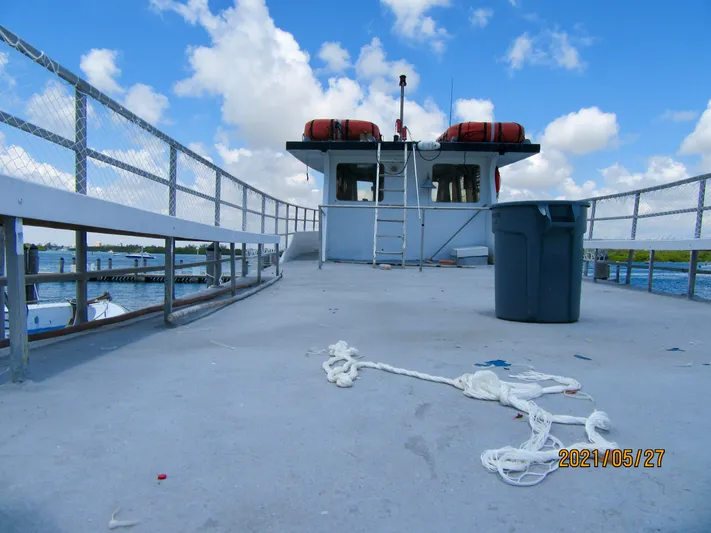 Atlantis Yacht Photos Pics Commercial drift fishing boat deck with ropes, trash bin, and life preservers under a blue sky.