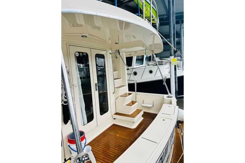 Tranquil Tides Yacht Photos Pics 2006 Mainship 34 Trawler with wooden deck and stairs in marina setting.