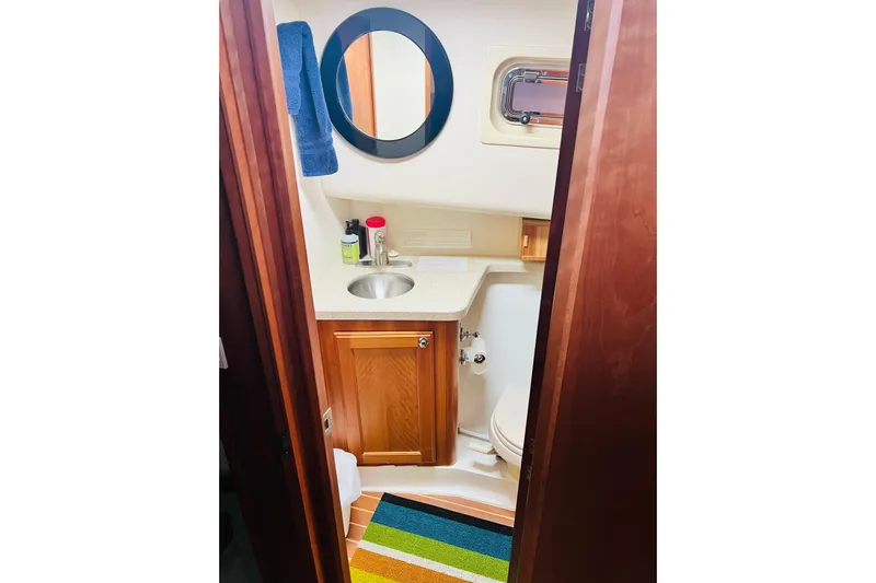 Tranquil Tides Yacht Photos Pics 2006 Mainship 34 Trawler bathroom with sink, mirror, and colorful rug.
