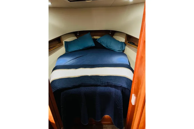 Tranquil Tides Yacht Photos Pics Cozy cabin bedroom in 2006 Mainship 34 Trawler with blue bedding and pillows.