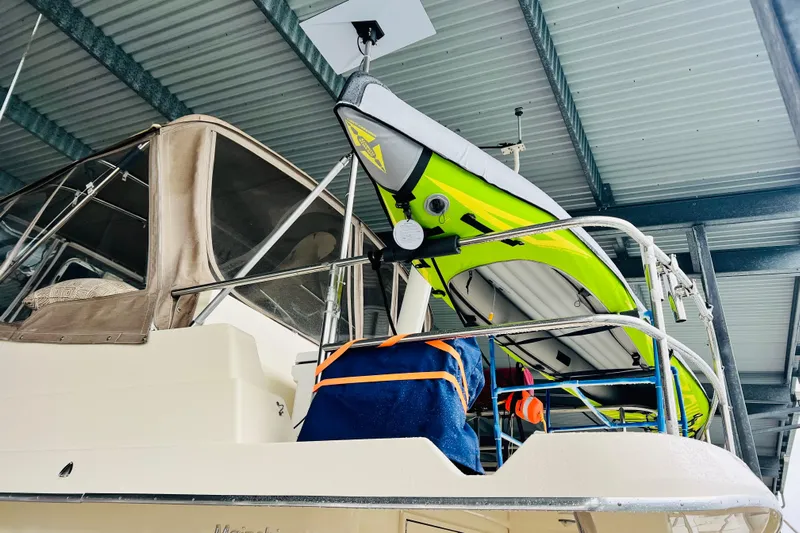 Tranquil Tides Yacht Photos Pics 2006 Mainship 34 Trawler with kayak and gear on deck under a metal roof.