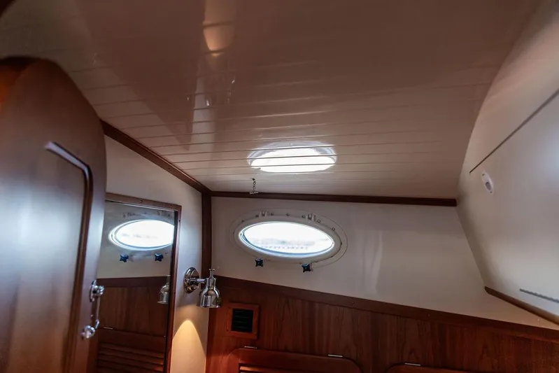 Brendan Yacht Photos Pics Interior of 2018 Hinckley Picnic Boat 37 MKIII with wooden paneling and porthole window.