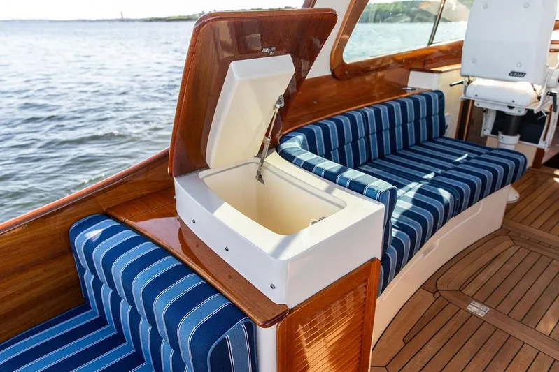 Brendan Yacht Photos Pics 2018 Hinckley Picnic Boat 37 MKIII interior with blue striped seating and open storage compartment.