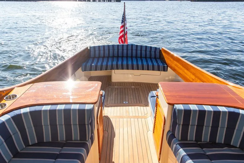 Brendan Yacht Photos Pics 2018 Hinckley Picnic Boat 37 MKIII with striped seating, wooden deck, and American flag on water.