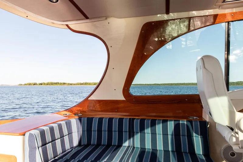 Brendan Yacht Photos Pics Interior view of 2018 Hinckley Picnic Boat 37 MKIII with striped seating and scenic water backdrop.