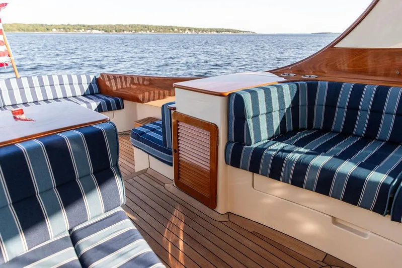 Brendan Yacht Photos Pics 2018 Hinckley Picnic Boat 37 MKIII with striped seating and wooden deck on a calm lake.