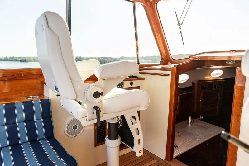 Brendan Yacht Photos Pics Helm station of 2018 Hinckley Picnic Boat 37 MKIII with white captain's chair and wooden interior.